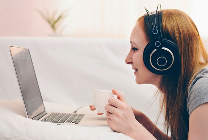 Young woman listening to music on her laptop with headphones