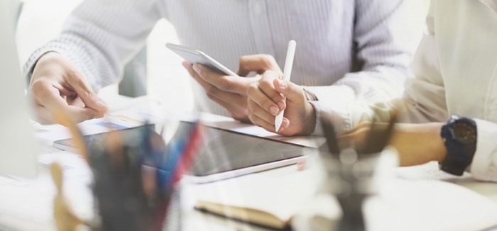 Two people reviewing documents on smartphone and tablet