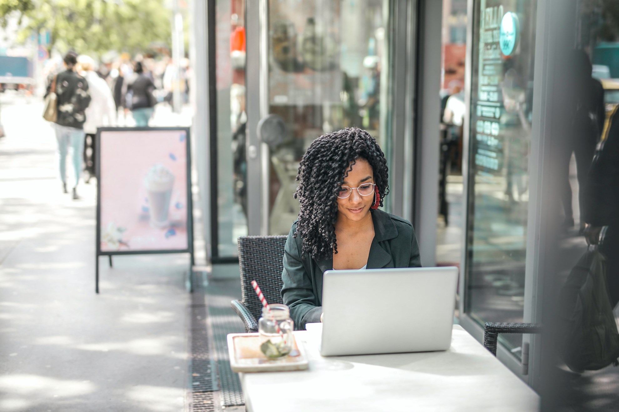 Woman at streetside cafe searching for properties on a laptop